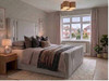 Aura Ottoman bed frame upholstered in silver velvet, featuring custom chrome accents on the tall headboard and footboard.
