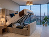 Beige velvet Chantal Ottoman bed in the open position, demonstrating the smooth lifting mechanism and large internal storage capacity
