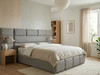​A beautifully tailored ottoman bed frame in Grey Tweed fabric, complete with a custom extended headboard, centered in a warm and inviting modern bedroom.