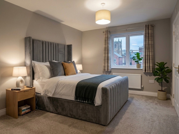 Grey velvet ottoman bed frame featuring a tall, vertical channel-tufted wingback headboard.