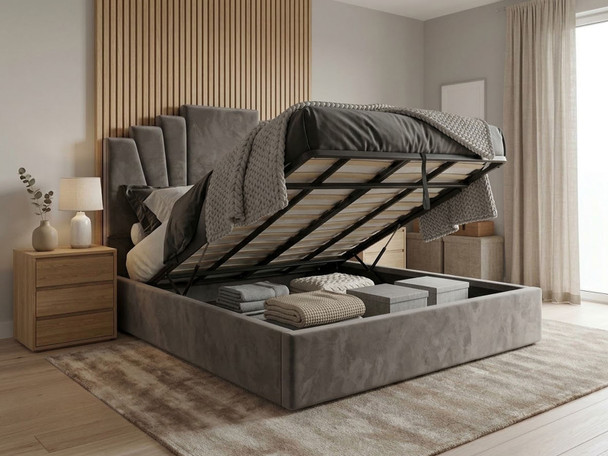An upholstered ottoman bed frame in a grey velvet fabric, with the mattress base lifted open to reveal a large internal storage area.