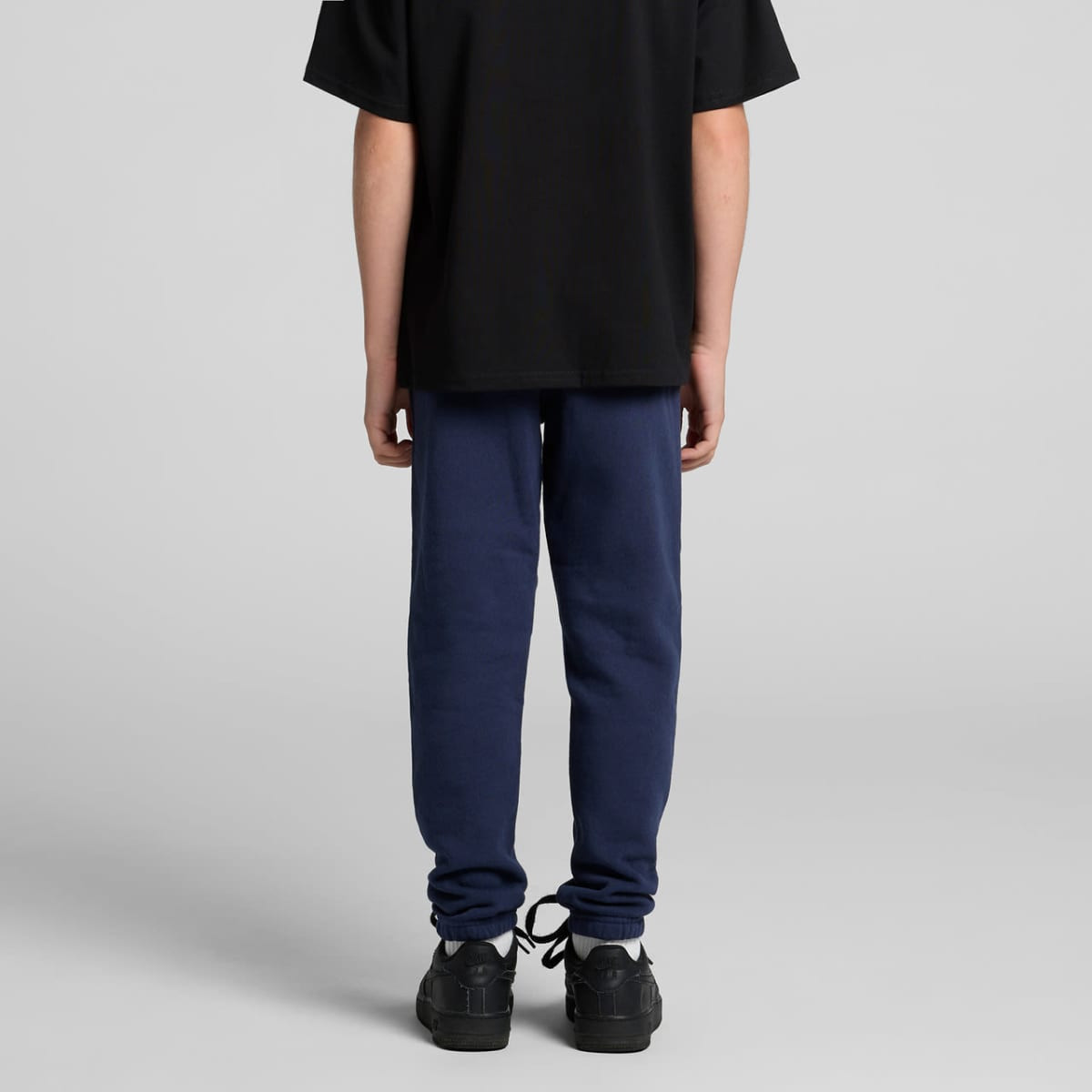 Navy track pants with a fitted design, featuring elasticised cuffs, paired with a black t-shirt and shoes.