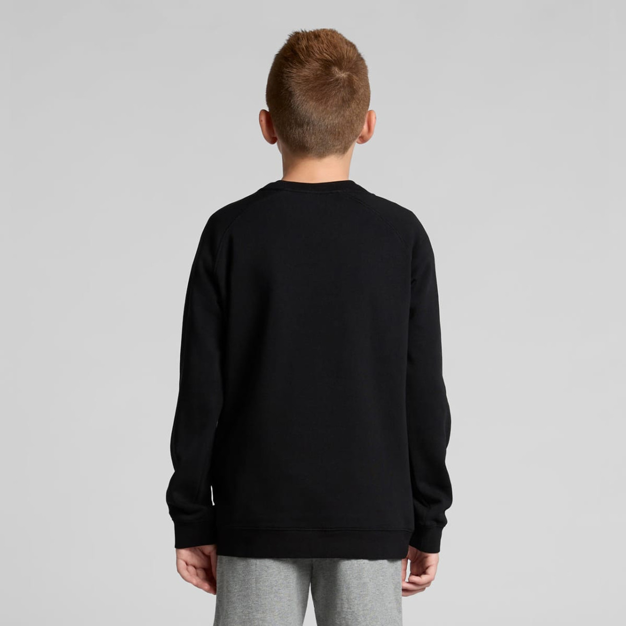 A black jumper for youth, featuring long sleeves and a simple design, seen from the back.