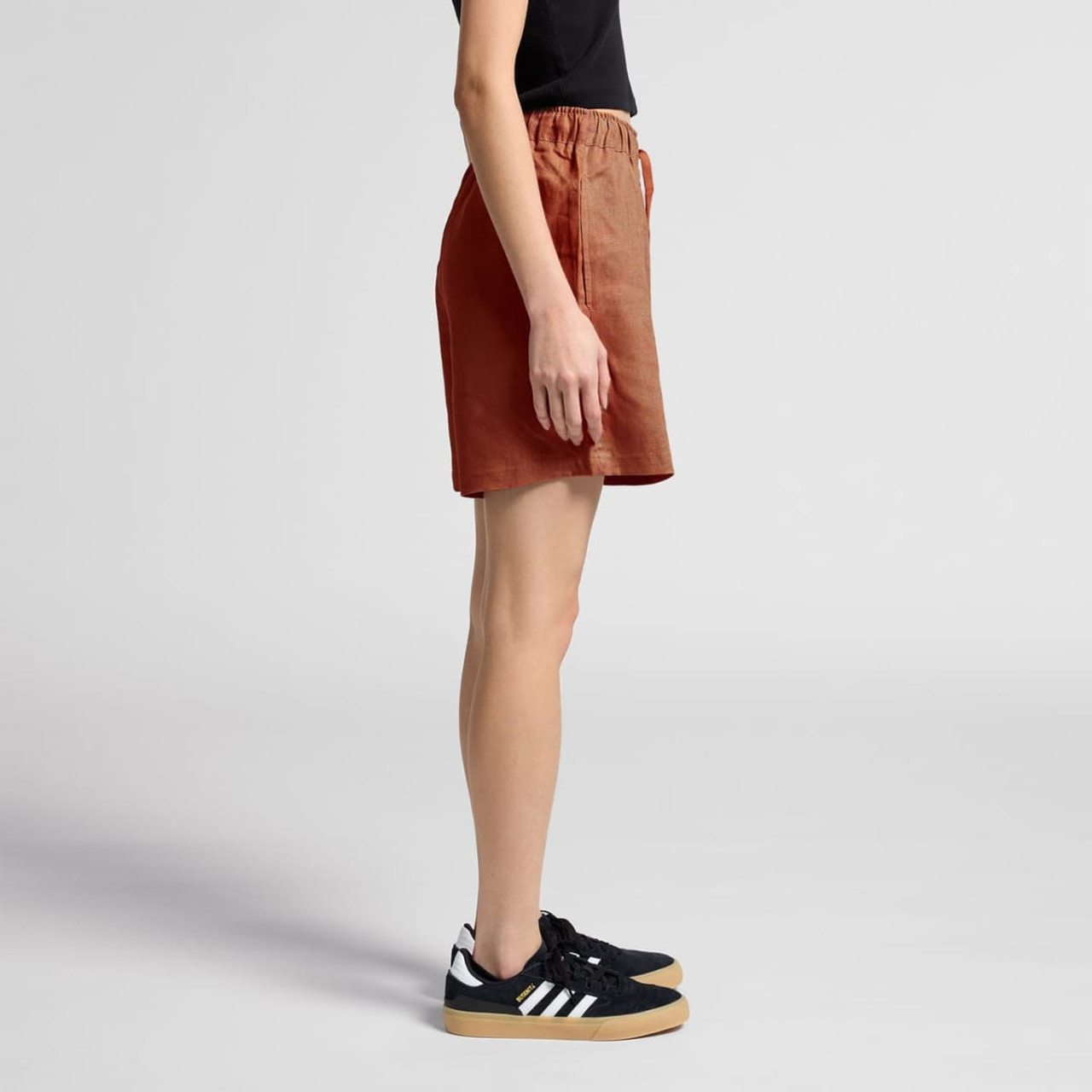 Linen shorts in a warm terracotta colour, with an elastic waistband and relaxed fit, styled with black sneakers.
