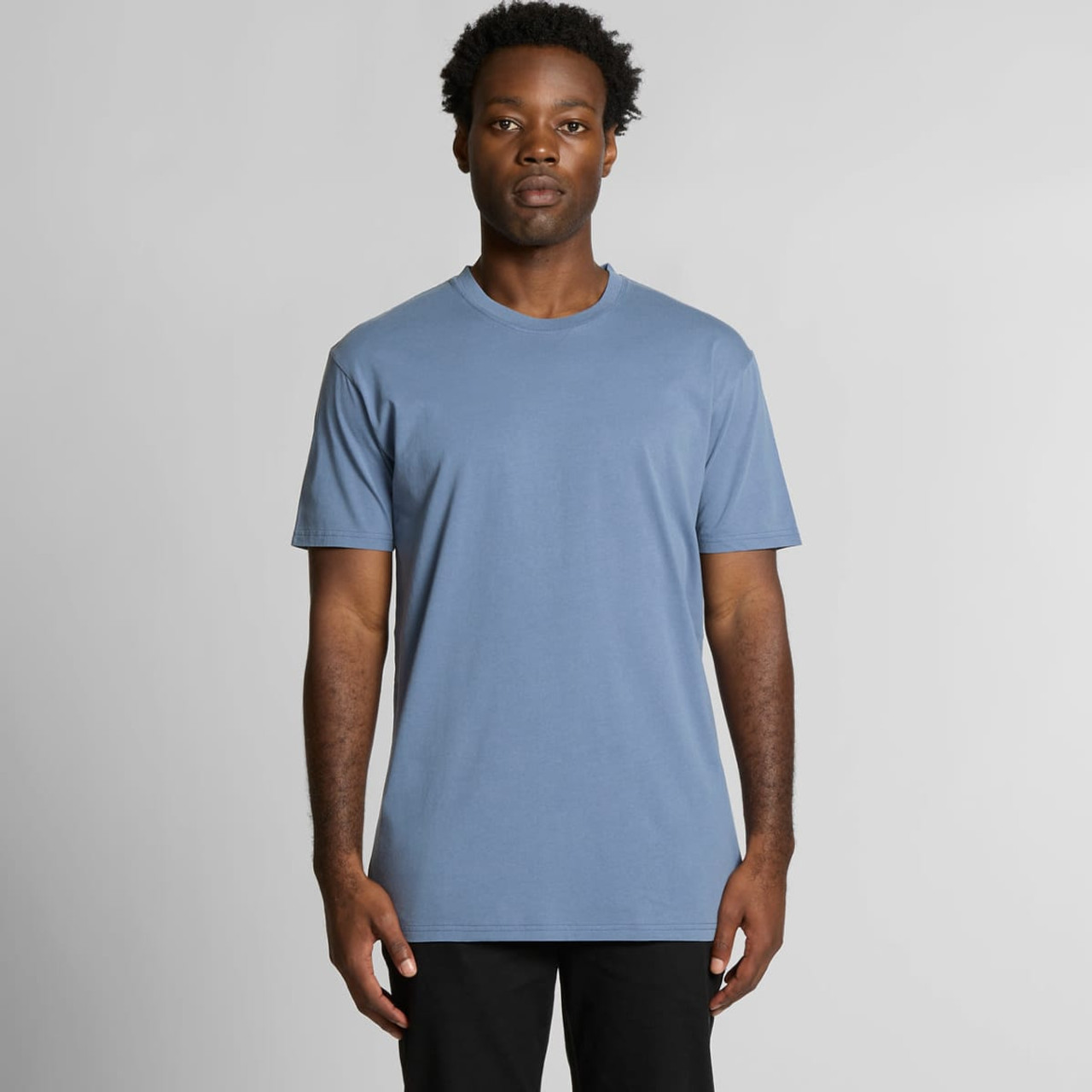 A blue t-shirt featuring a simple design, short sleeves, and a round neck. The model stands against a plain background.