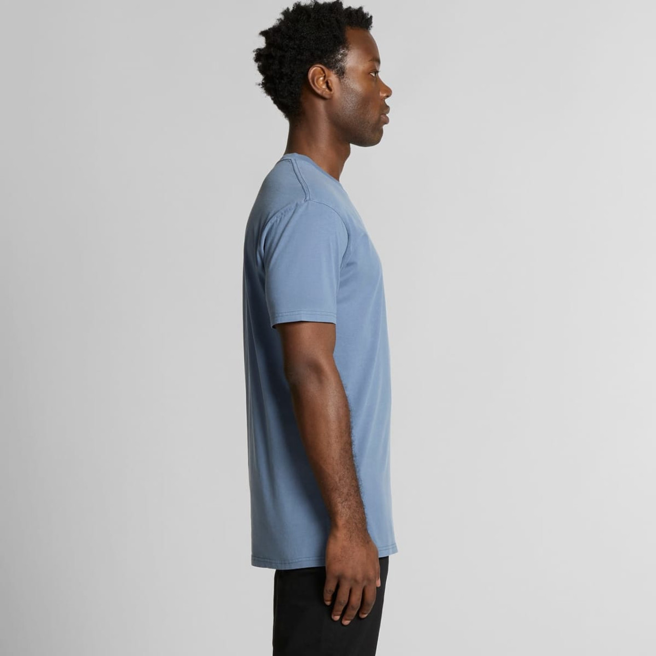 A casual blue T-shirt featuring a simple design and a logo, modelled by a person from the side.