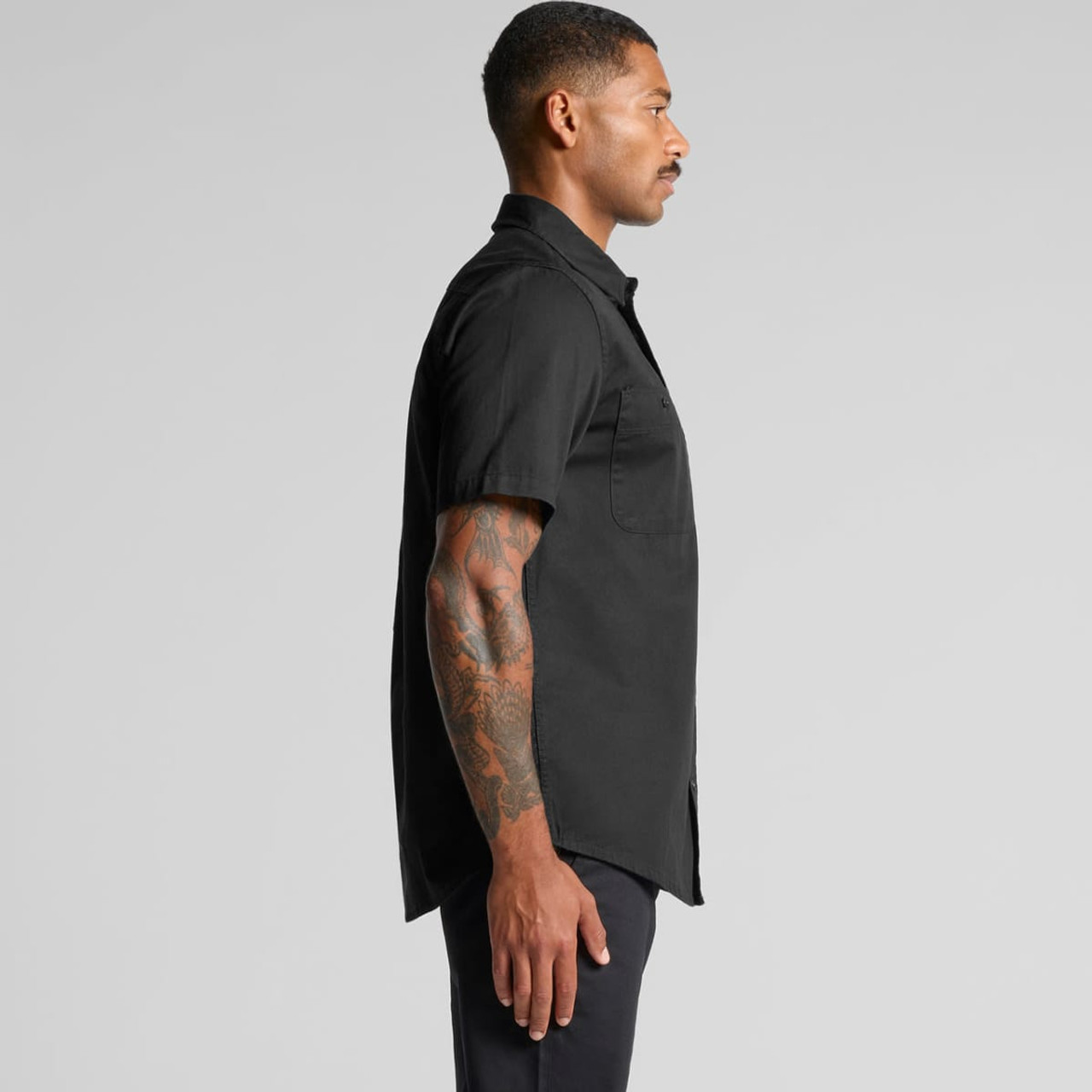 A black short-sleeve work shirt displayed on a model, showcasing a side profile view and a pocket detail.