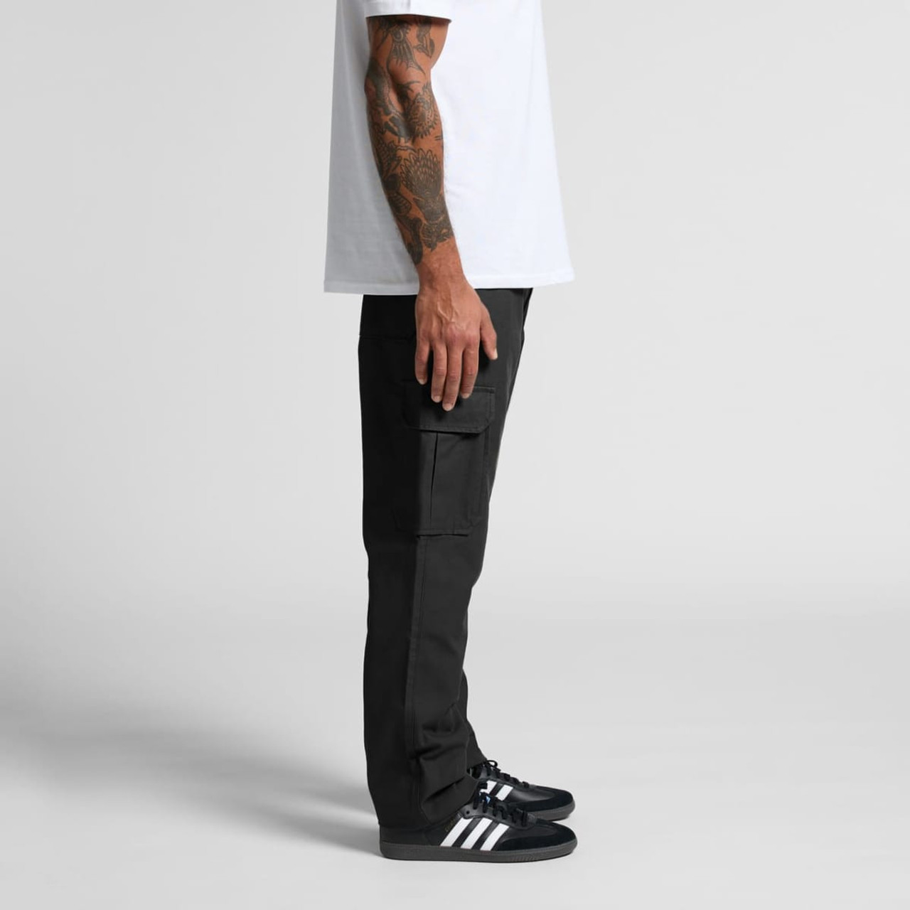Utility cargo pants in black displayed on a model from the side, paired with black sneakers and a white t-shirt.