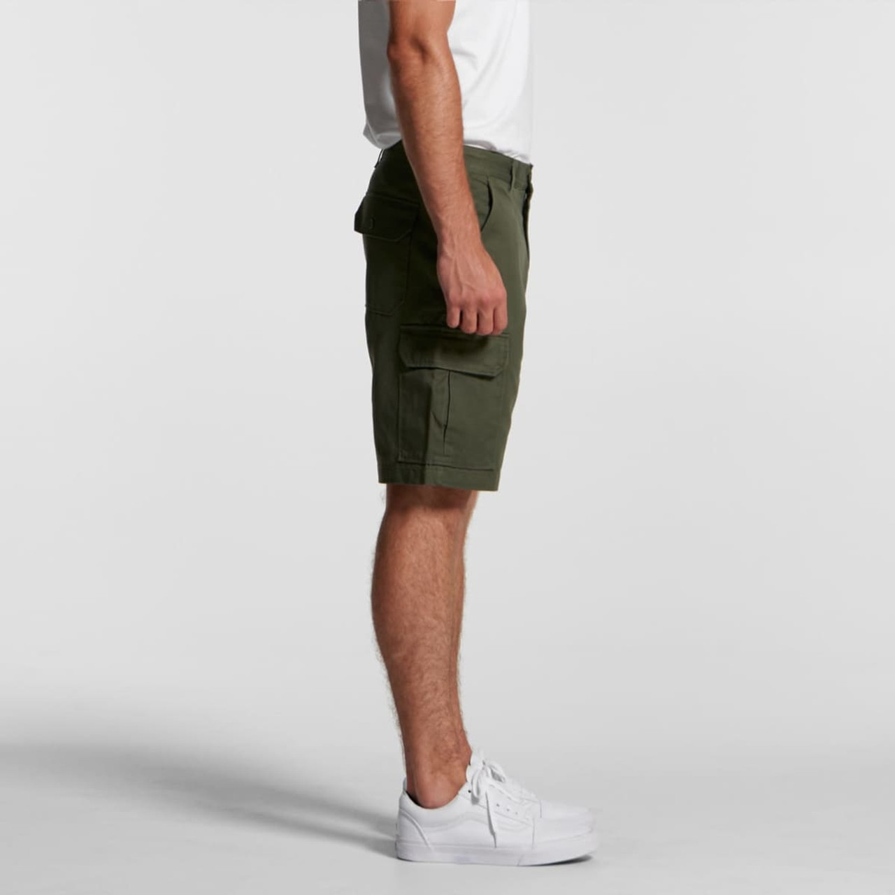 Cargo shorts in olive green displayed on a model, featuring side pockets and styled with white sneakers.