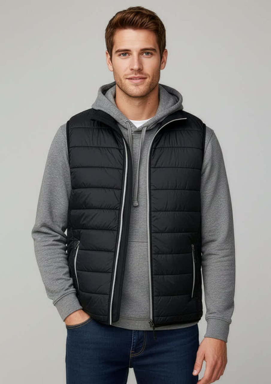 A black puffer vest worn over a grey hoodie, modelled by a man, featuring a zip front and a logo.