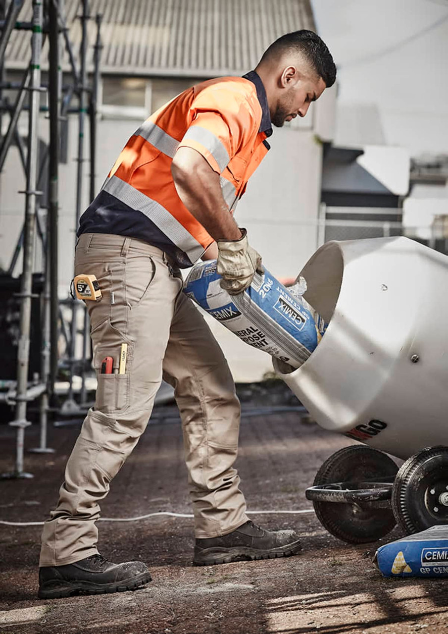 Men’s cargo pants in beige, featuring multiple pockets, worn by a worker pouring materials into a mixer.
