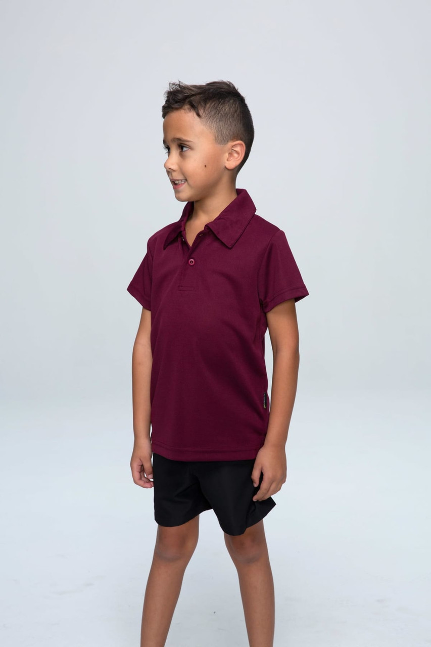A maroon children's polo shirt with a collar, displayed on a young boy wearing black shorts. The shirt has a logo.