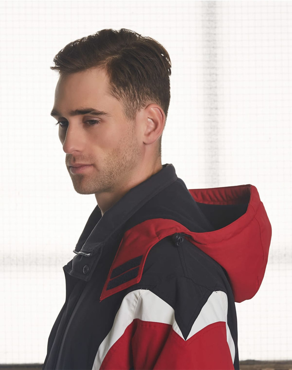 A tri-colour jacket with a hood featuring navy, red, and white sections. It has a logo on the shoulder.