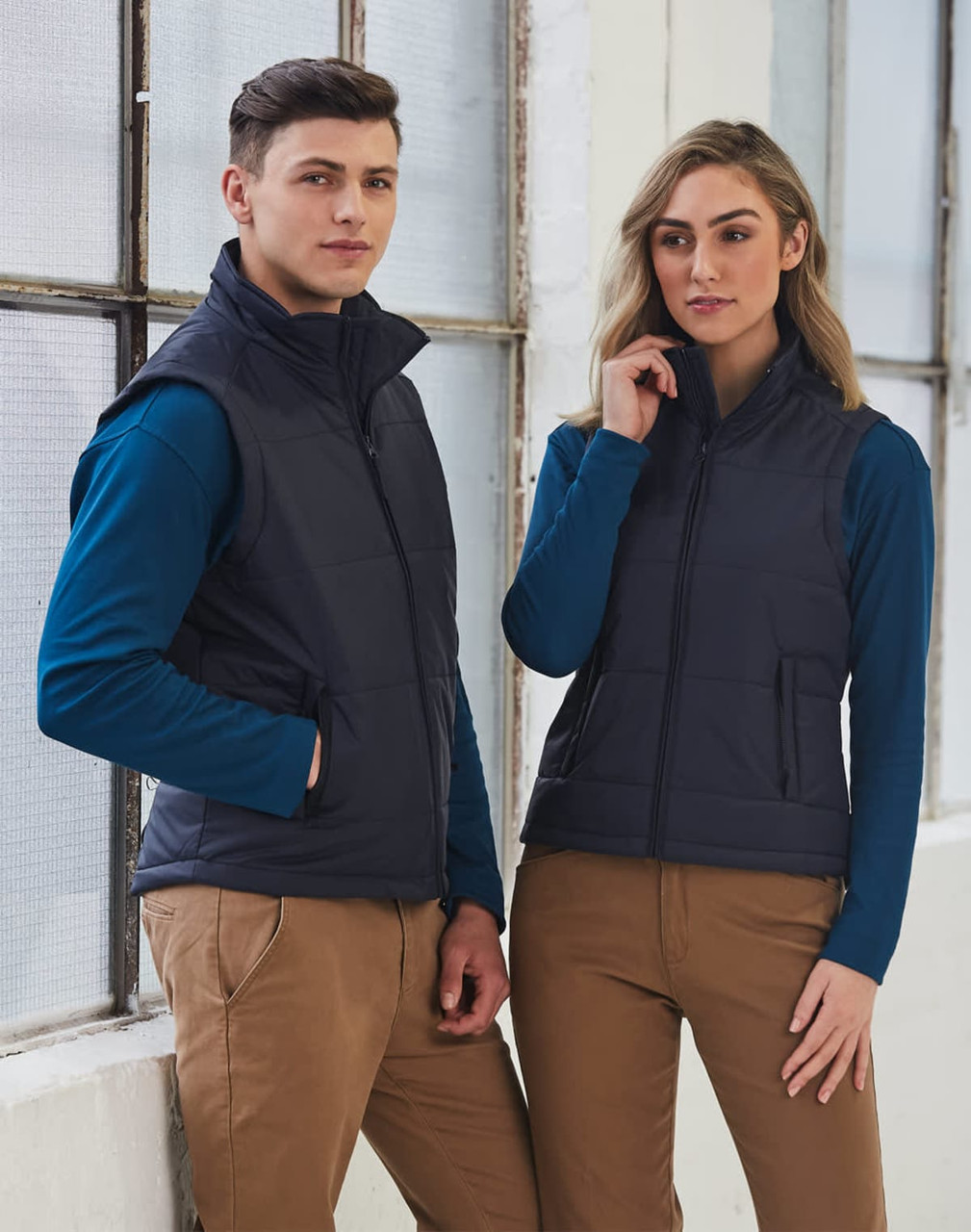 A navy nylon rip-stop padded vest displayed on a male and female model, featuring zipped pockets and a stylish design.