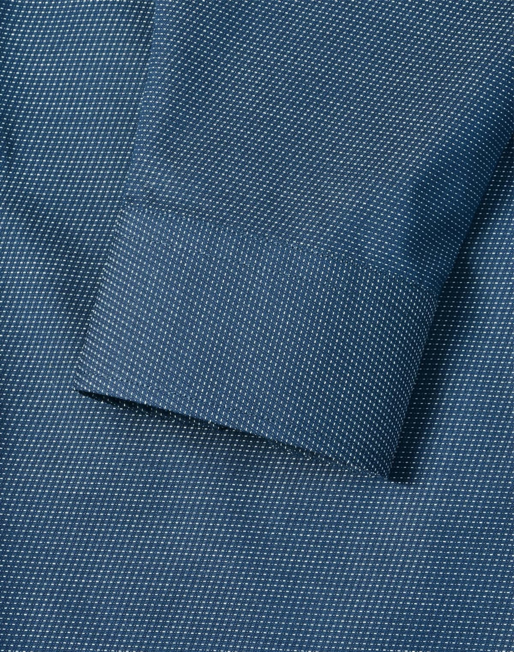 A detailed close-up of a blue men's button-up shirt featuring a pin dot pattern and a cuff.