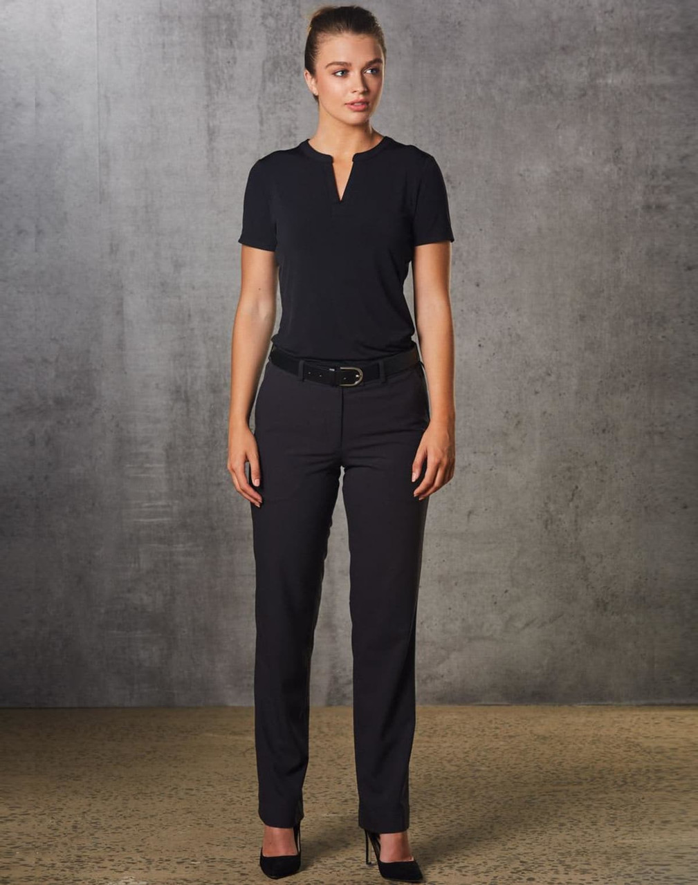 A woman wearing black Women's Flexi Waist Utility Pants, paired with a matching top, standing against a textured background.