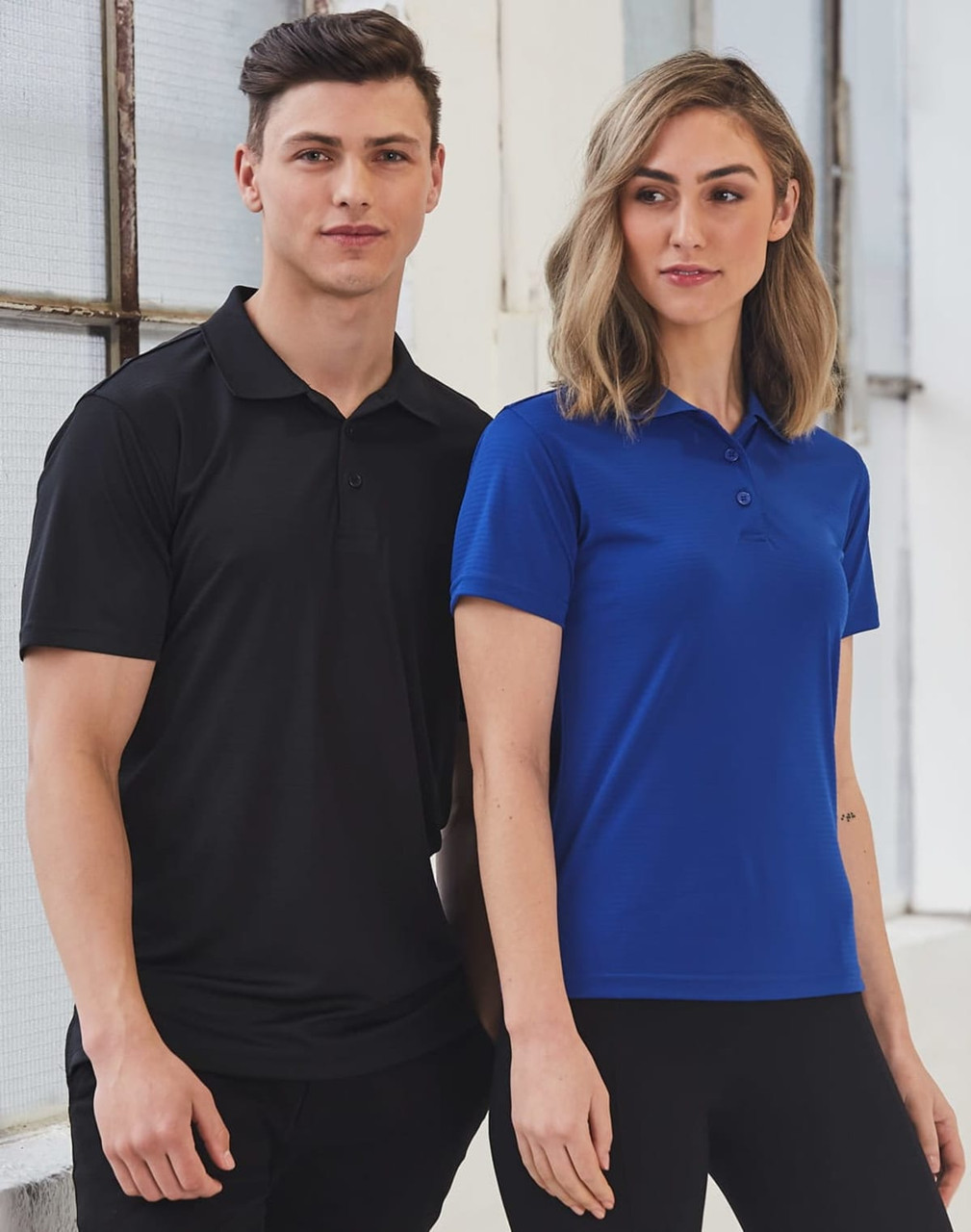 A textured polo shirt for ladies in blue, displayed alongside a black polo shirt for men, both featuring logos.