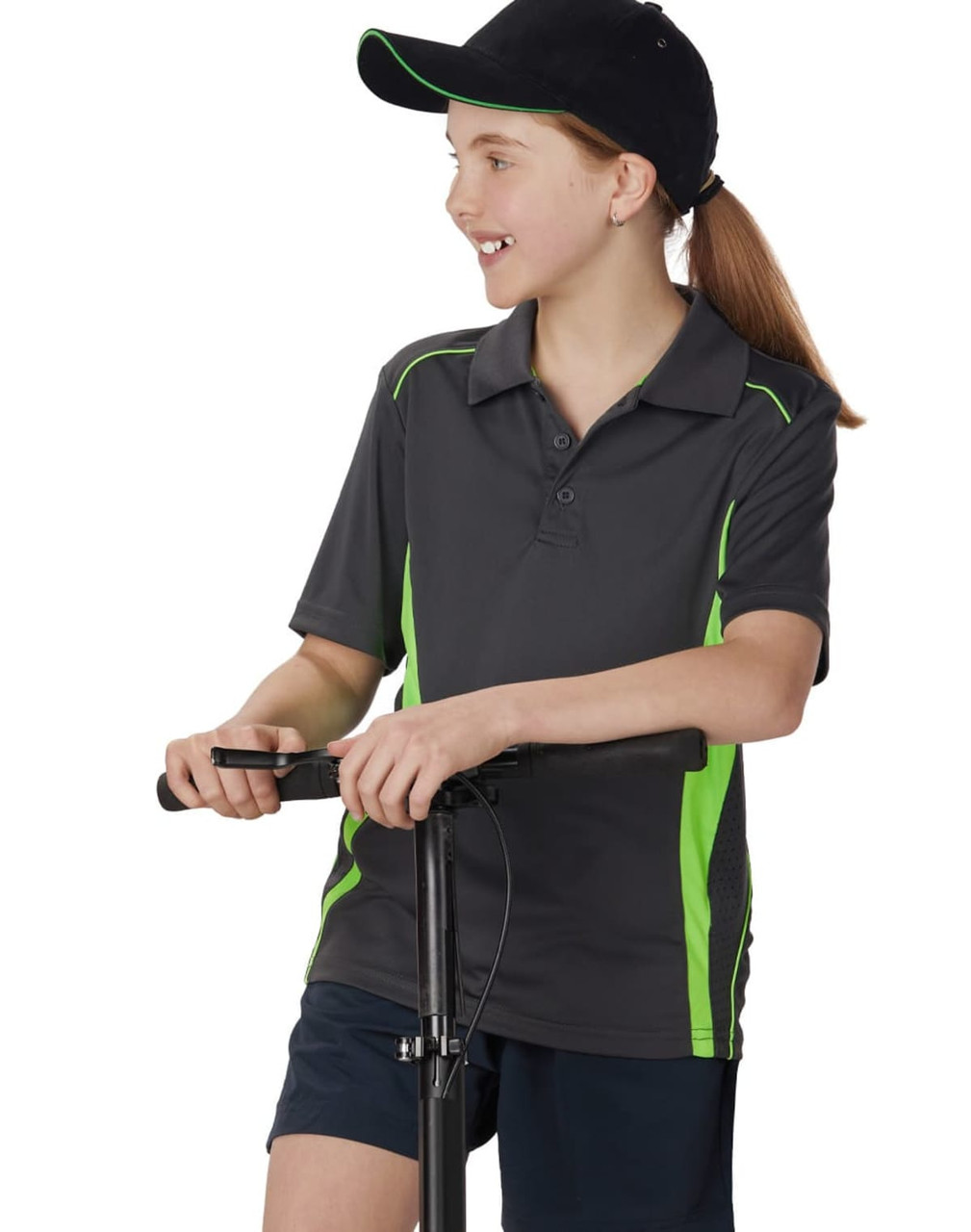 A child wearing a dark grey polo shirt with lime green contrast details, standing next to a scooter.
