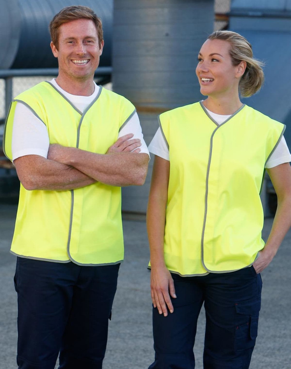 A hi-vis safety vest in bright yellow, worn by two smiling individuals. The vests feature a grey trim and have a logo.