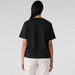 A black boxy tee featuring short sleeves and a simple cut, worn with light-coloured dress shorts.