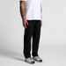Relaxed pants in black, featuring a straight fit. A person stands wearing them with a white shirt and sneakers.
