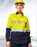 A long-sleeve safety shirt in bright yellow and navy, featuring reflective tape and a logo, worn by a model in a hard hat.