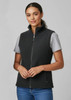 A women's plain micro fleece vest in black, featuring a front zipper and a high collar. Model wears a grey shirt underneath.