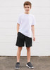 A young boy poses in a white t-shirt paired with black sports shorts, standing against a white wall.