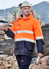 Men's hi-vis waterproof jacket in bright orange with reflective stripes, paired with a hard hat and work gloves.