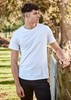A white men's T-shirt is worn by a model standing beside a wooden fence in an outdoor setting.