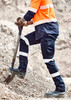 Mens Essential Stretch Taped Cargo Pant in navy blue with reflective stripes, worn by a person shovelling gravel.