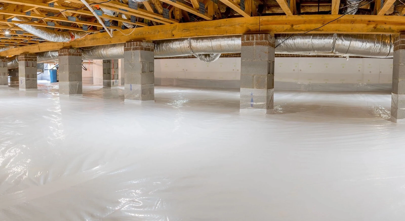 Clean encapsulated crawl space with a white vapor barrier installed across the floor and walls