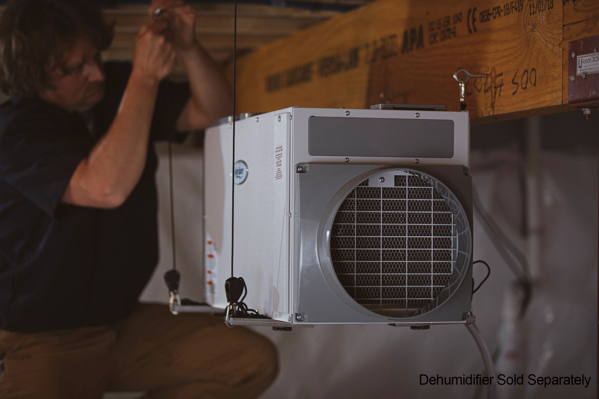 A technicians hangs the Aprilaire dehumidifier with a hang kit