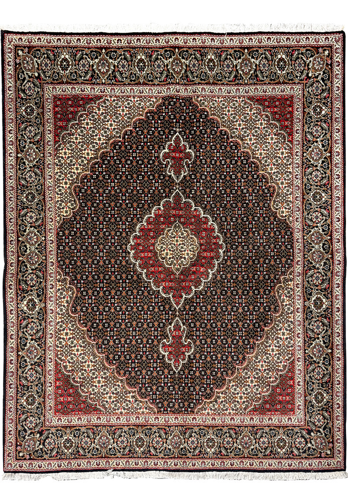 "Persian Tabriz Mahi rug edge detailing, showcasing the fine weave and complex designs in beige, red, and navy on a dark background. "Persian Tabriz Mahi rug edge detailing, showcasing the fine weave and complex designs in beige, red, and navy on a dark background.