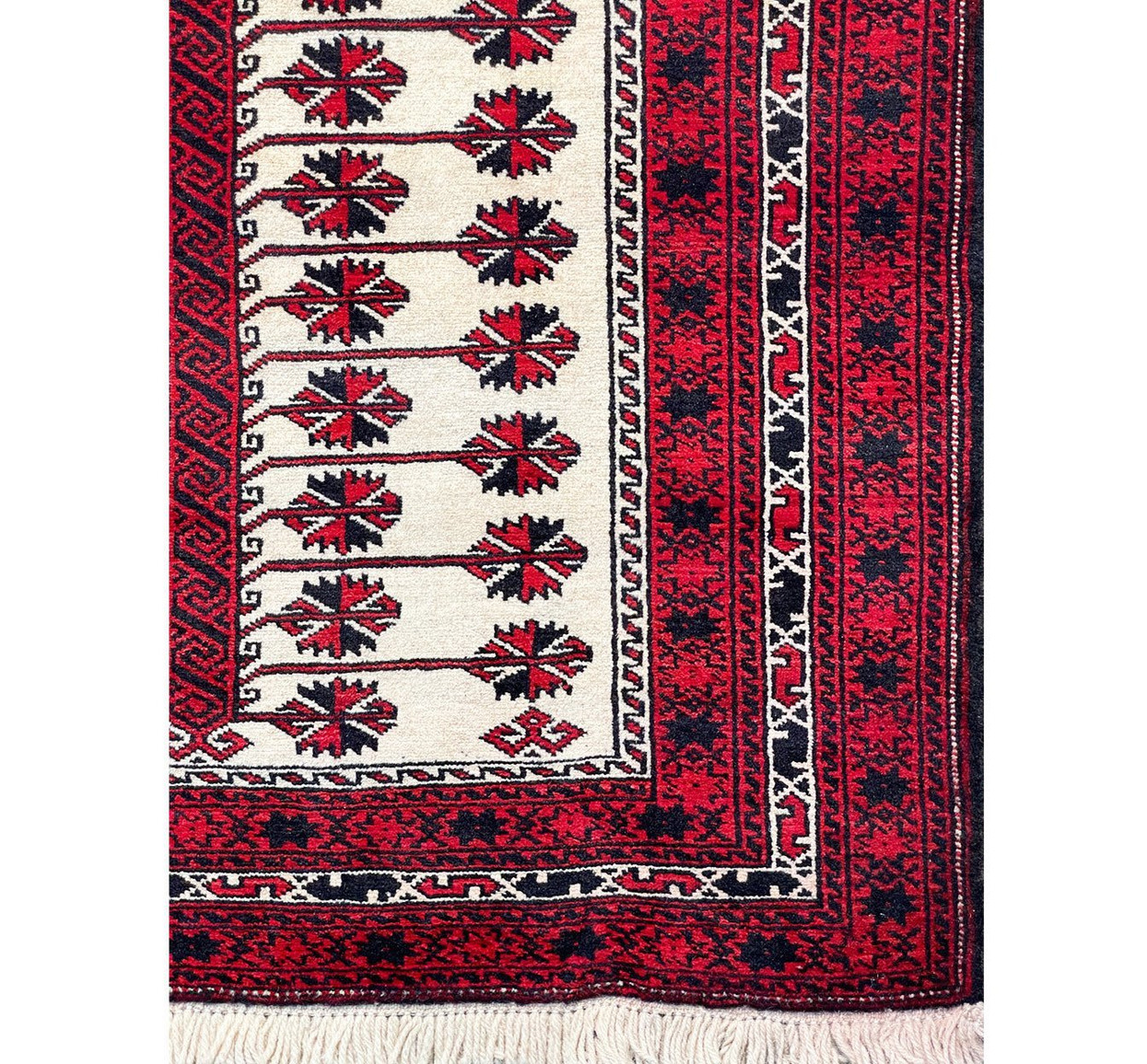 Border of the Persian Baluch rug with an intricate pattern of geometric shapes and floral motifs