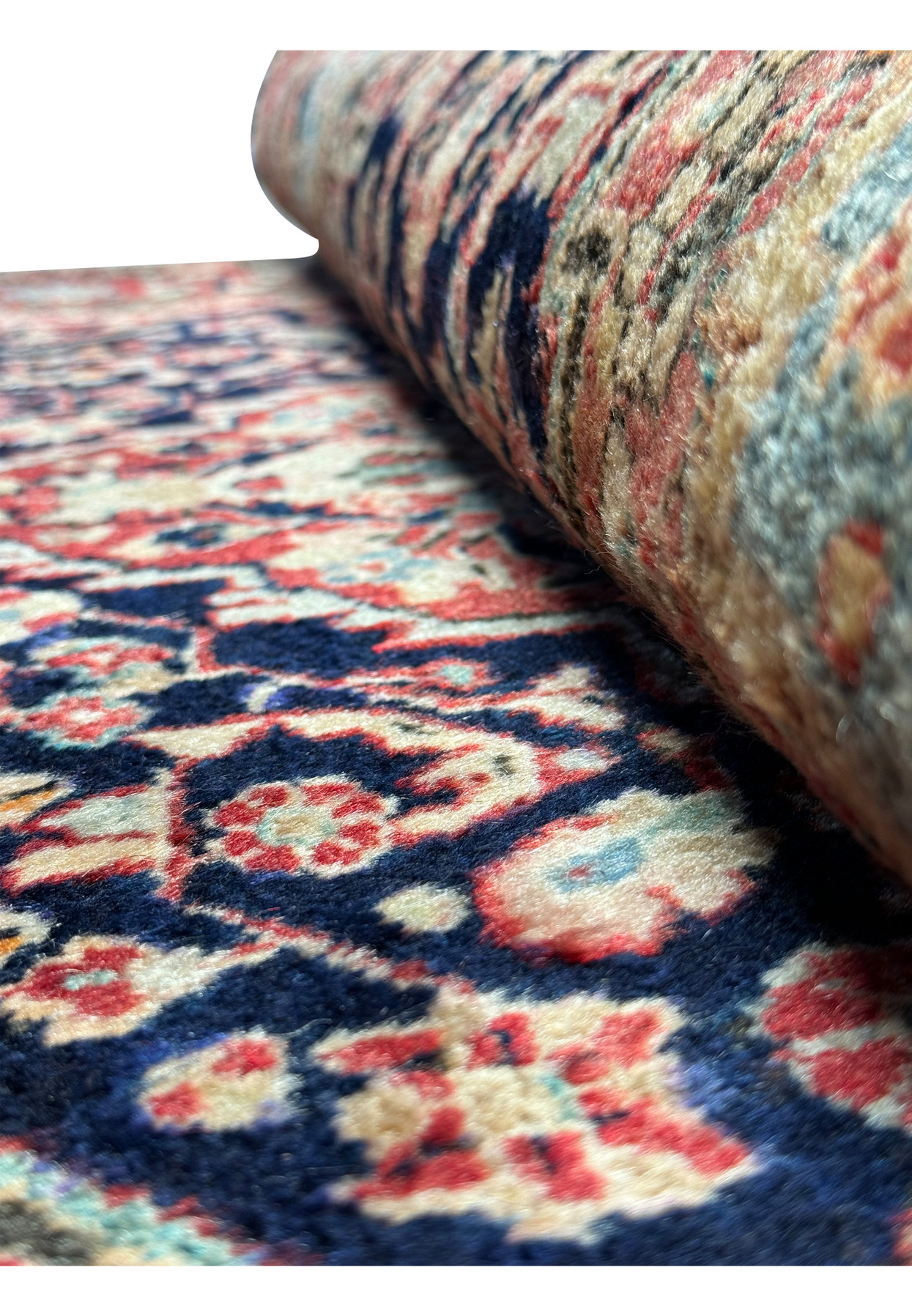 A perspective view of the Persian Sarough Rug, showing the texture and pile height, with visible color transitions between navy blue, red, and cream.