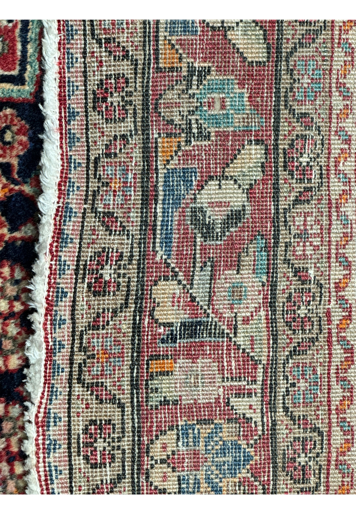 Macro detail of the rug's fringe and edge, showcasing the tight weave and edge binding alongside the detailed pattern work of the main rug body.