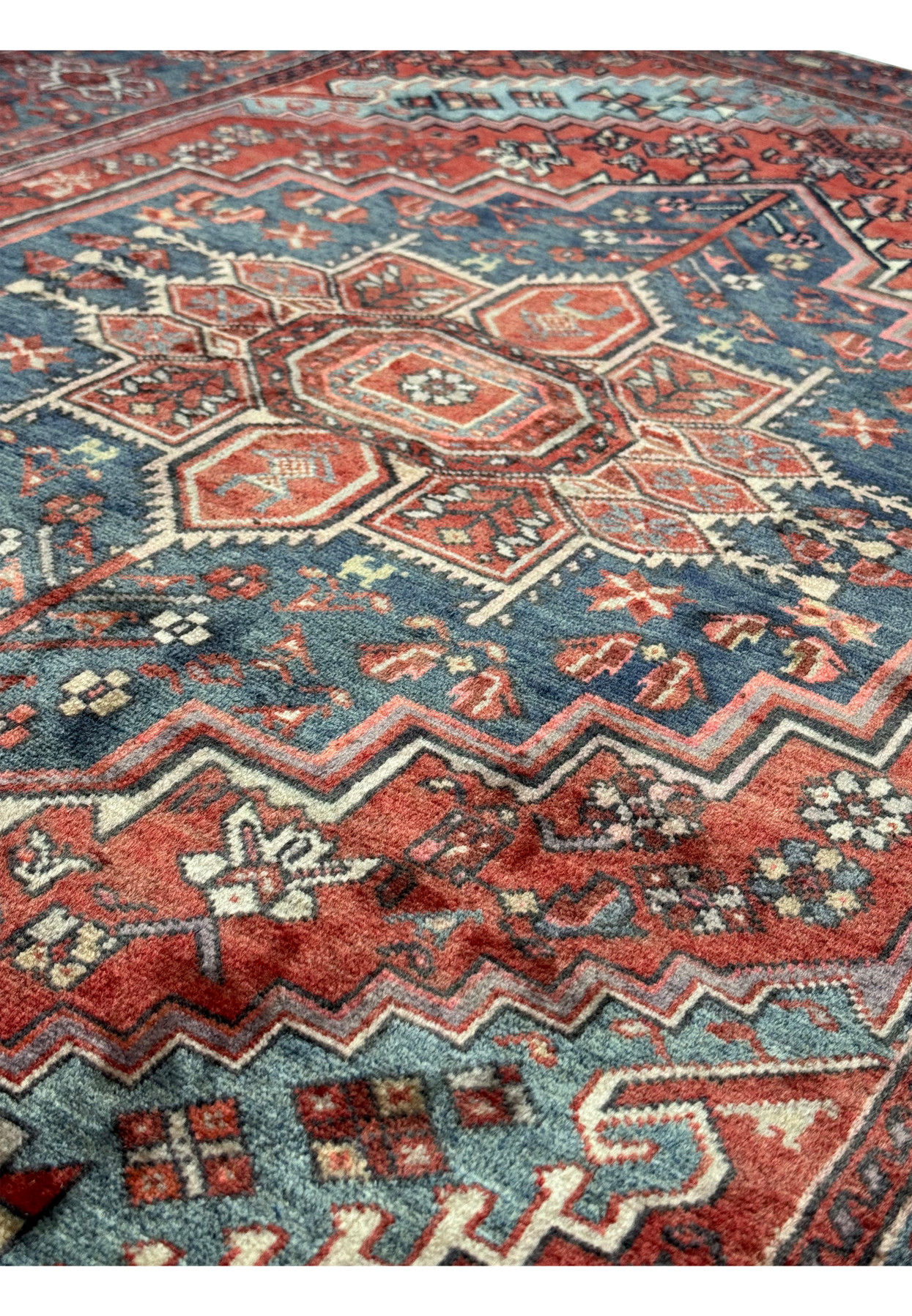 Angled close-up of a vintage Persian Bijar rug's surface, emphasizing the texture and the complexity of its geometric and floral motifs