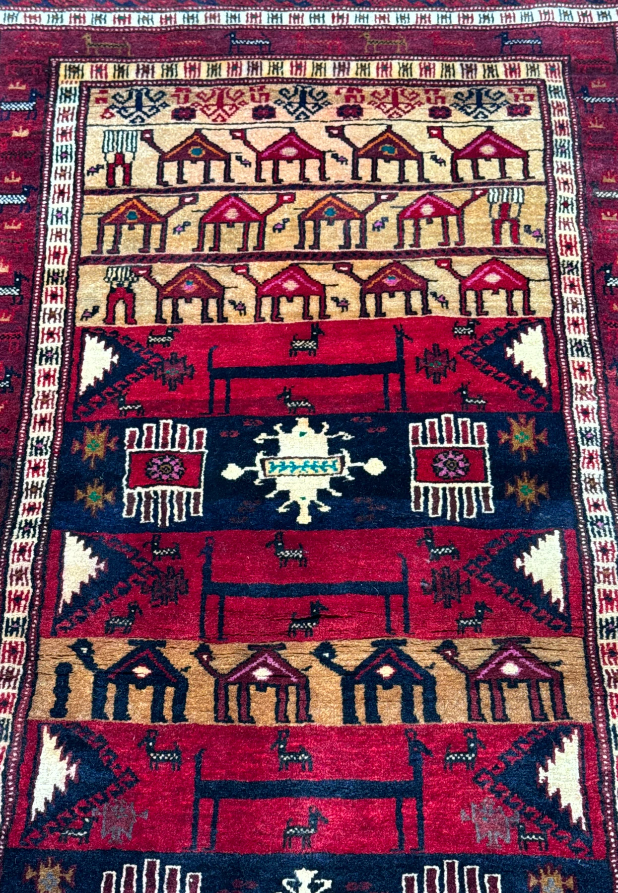 Focused image of the midsection of a Persian Baluch Tribal rug displaying symmetric tribal patterns and motifs