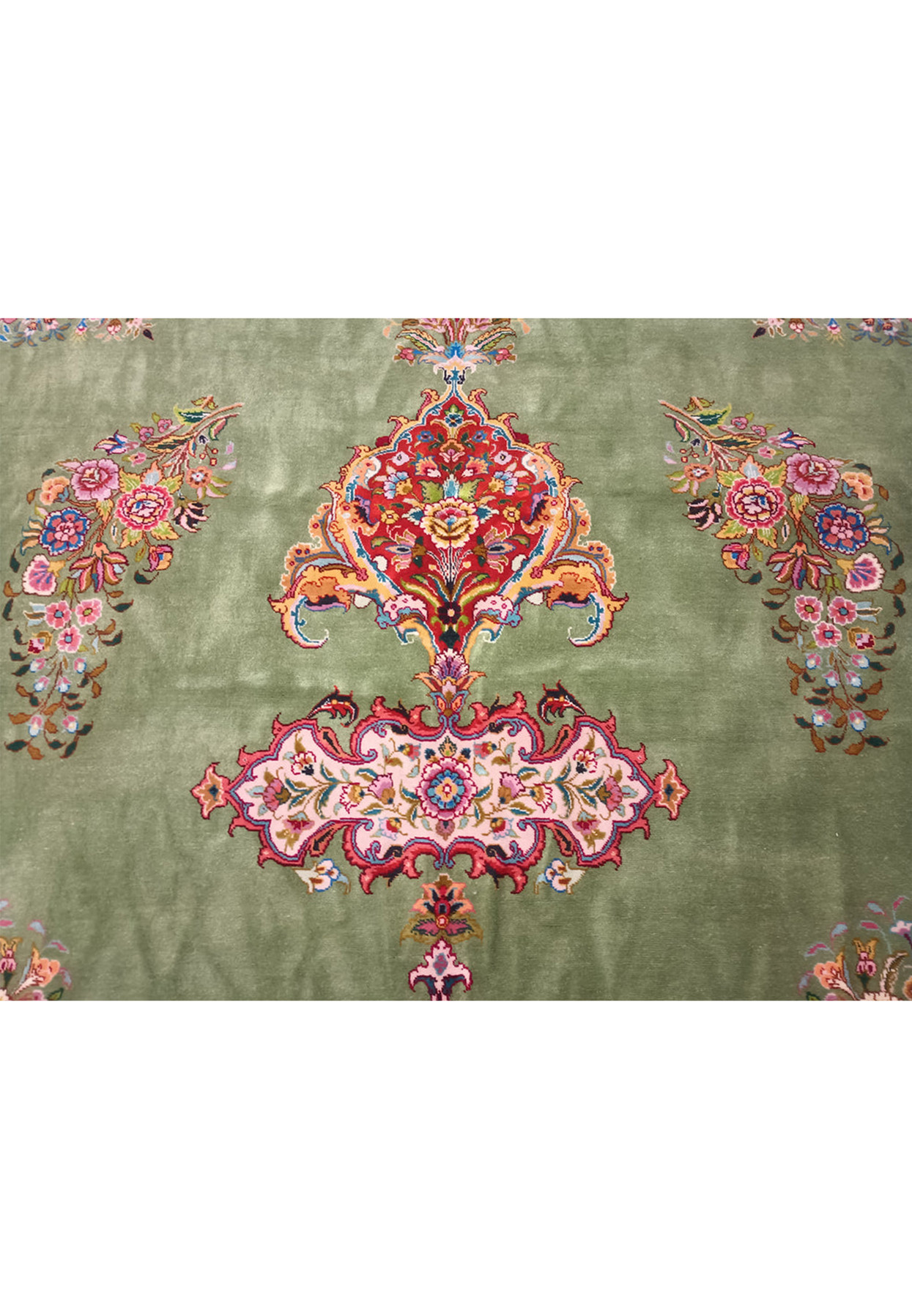 An overhead shot of a large Persian Tabriz rug, with emphasis on the symmetry and balance of the central design.
