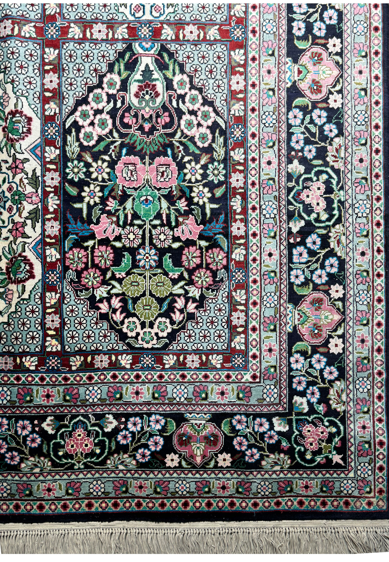 Corner detail of a Persian Qum silk rug, illustrating the delicate fringe and border pattern