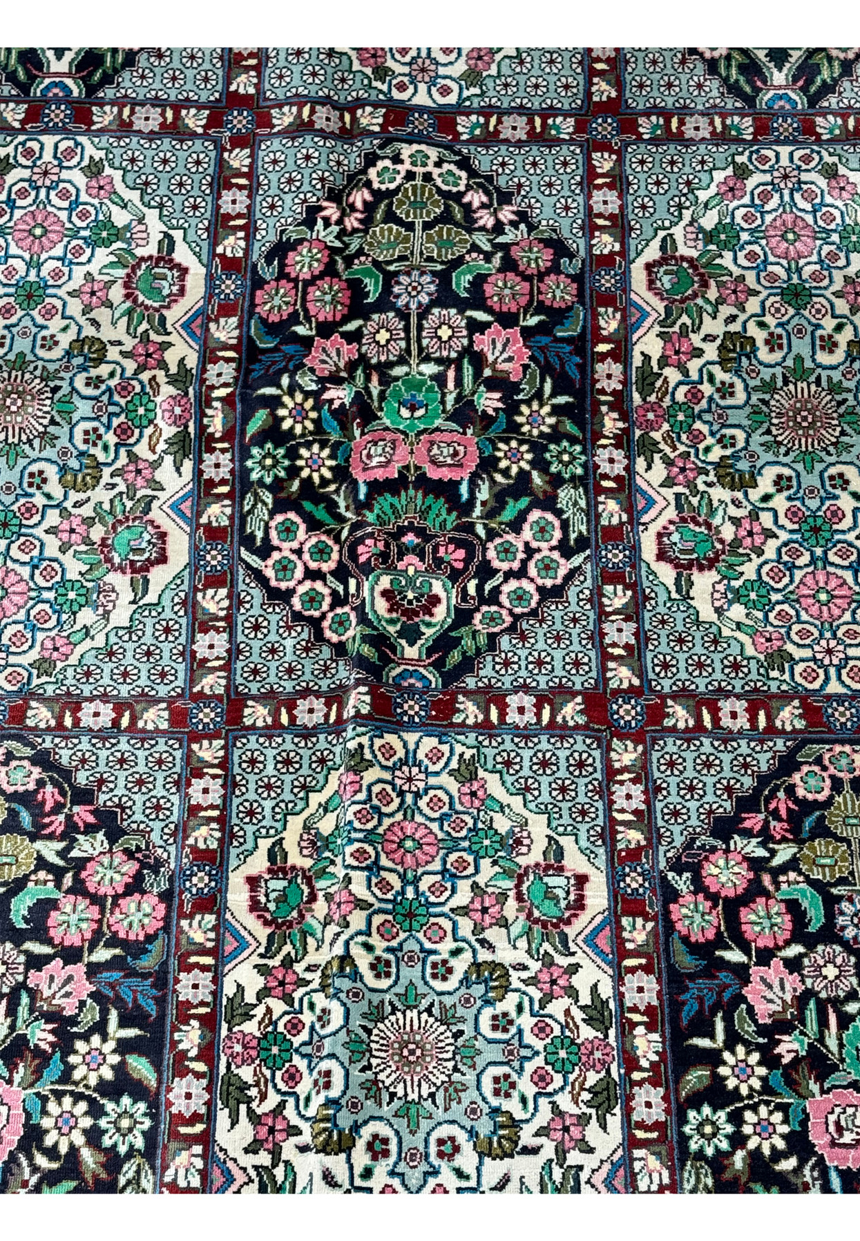 Detail of the central floral medallion on a Persian Qum silk rug, showcasing exquisite craftsmanship