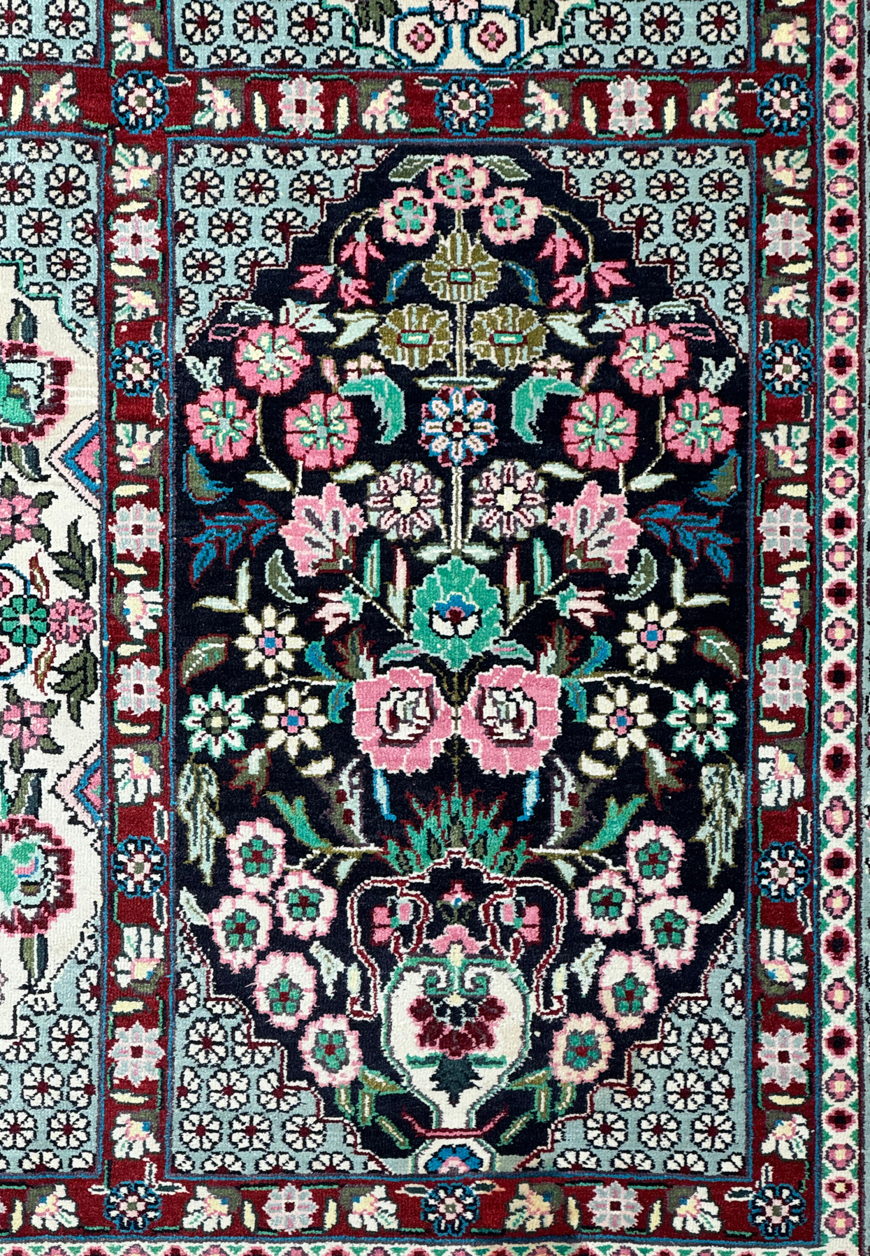High-angle view of a Persian Qum silk rug, emphasizing the symmetry of floral patterns and border design