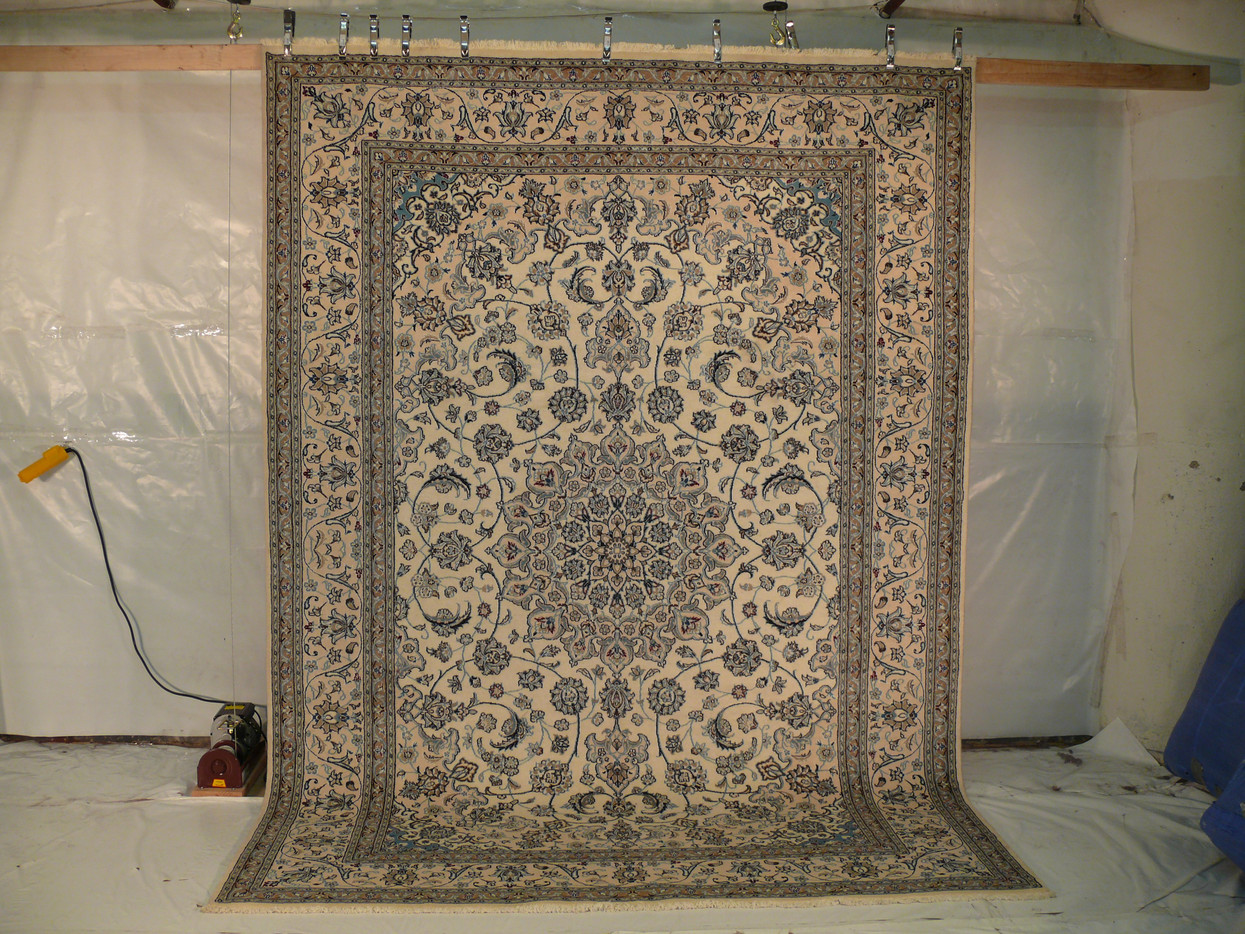 Angled view showing navy medallion with ivory and sky blue highlights on Persian Nain rug