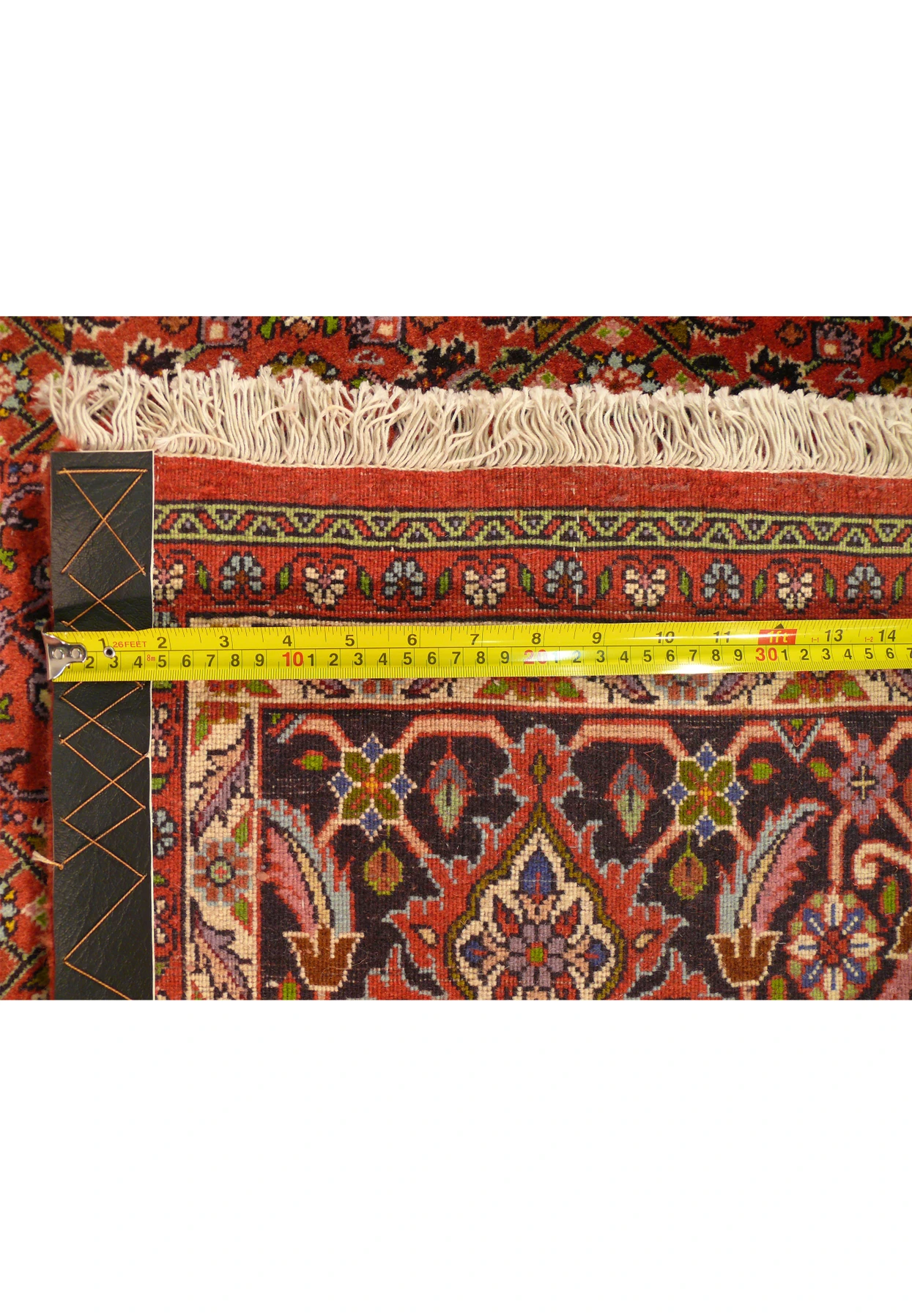 Diagonal view of a Persian Bijar rug showcasing the thickness and weaving structure with a measuring tape for scale