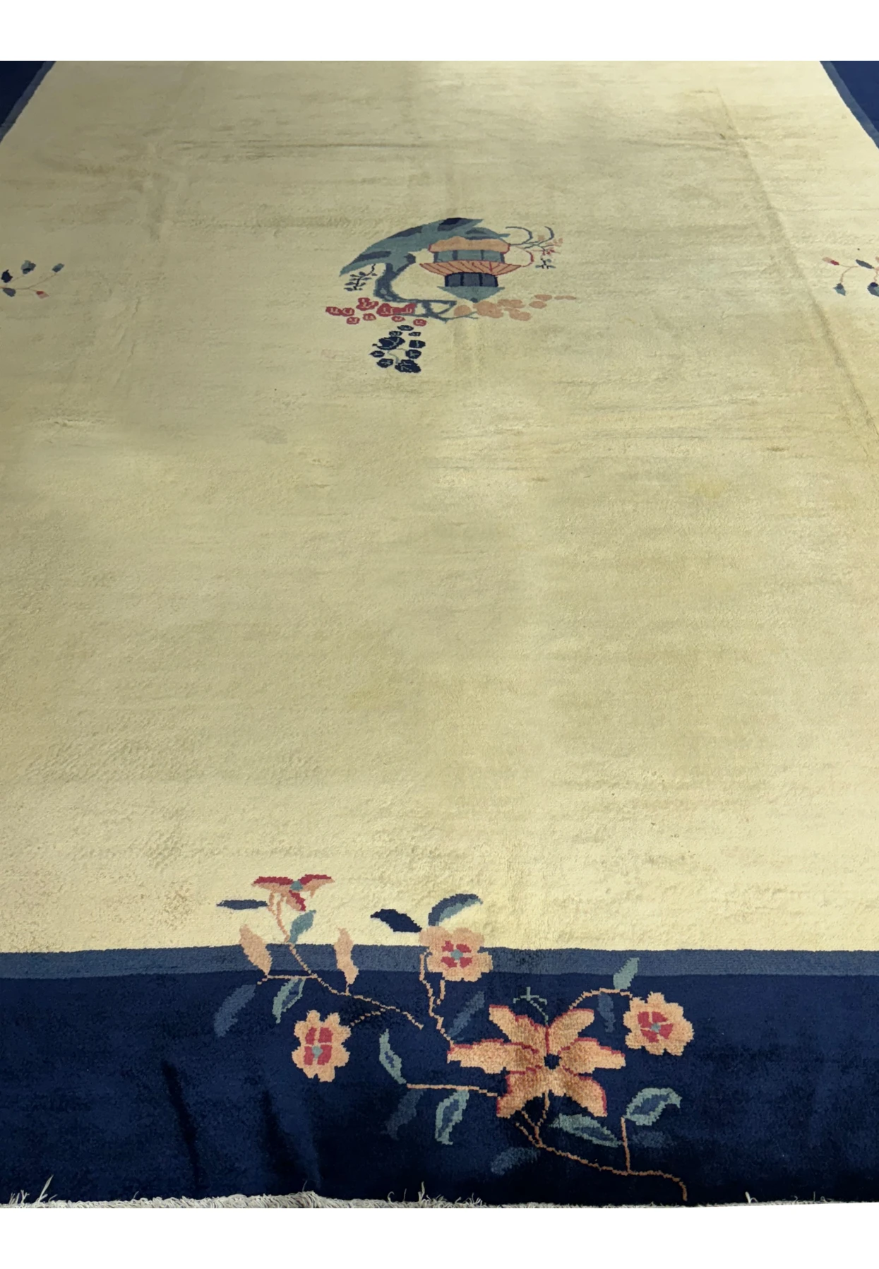 Close-up of the central part of a vintage Art Deco rug with a stylized vase motif surrounded by floral patterns on a beige background