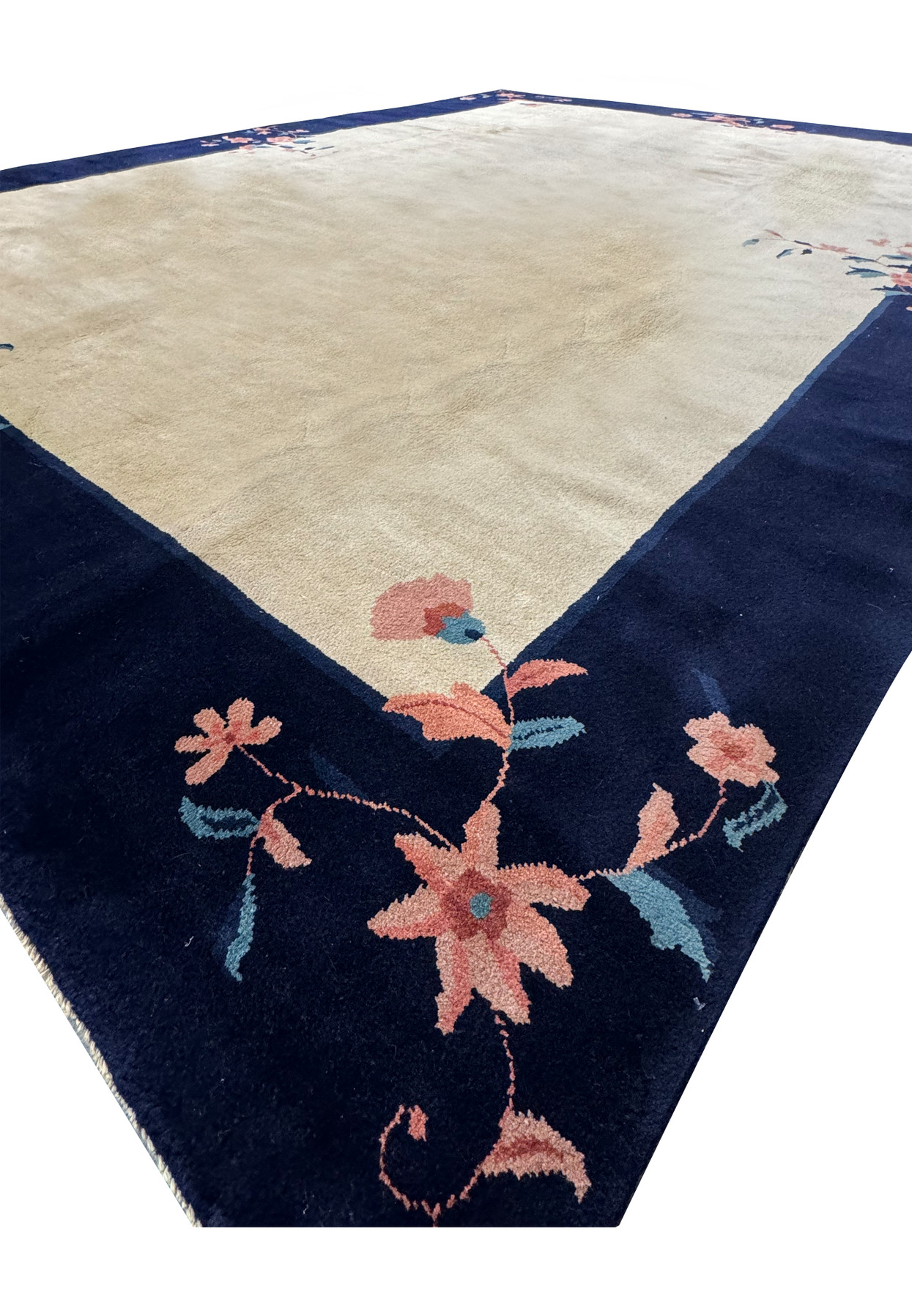 Angled perspective of an 8'2" x 11'2" Vintage Art Deco Rug, emphasizing the depth of the navy border against the ornamental beige center