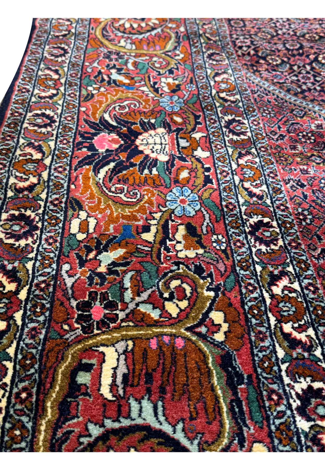 Close-up of the intricate geometric and floral patterns on the Persian Bijar rug with a navy blue and deep red color palette.