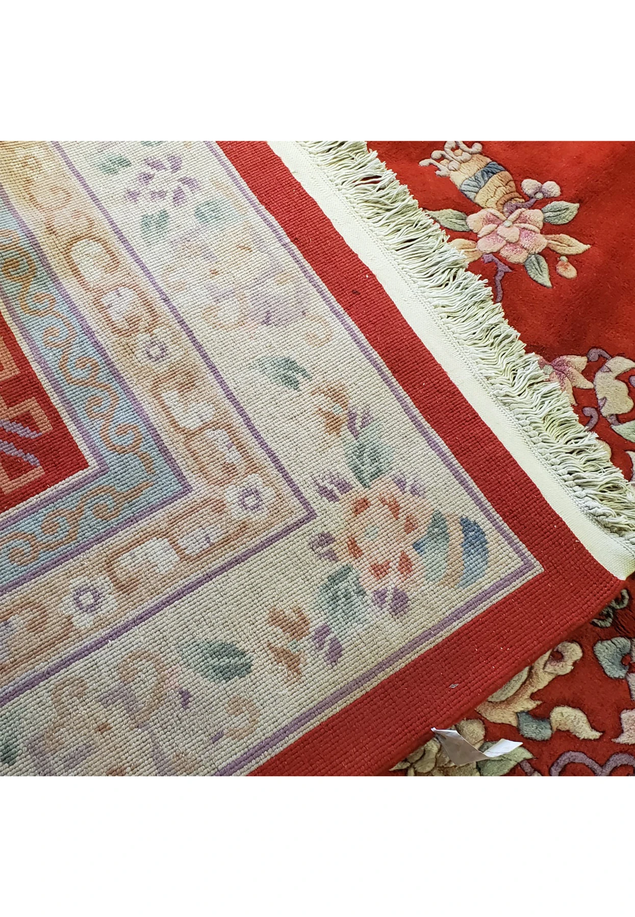 Edge view of an immaculate red Chinese Art Deco wool rug, showing the clean fringe and the rug's high-quality, shiny wool fibers in perfect condition.