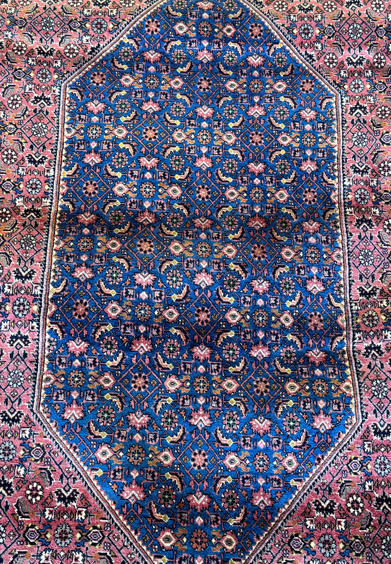 A Persian Bijar carpet of grand proportions, featuring a central medallion filled with a mosaic of symbols, framed by an intricate border, exemplifying the timeless beauty and precision of Persian rug-making